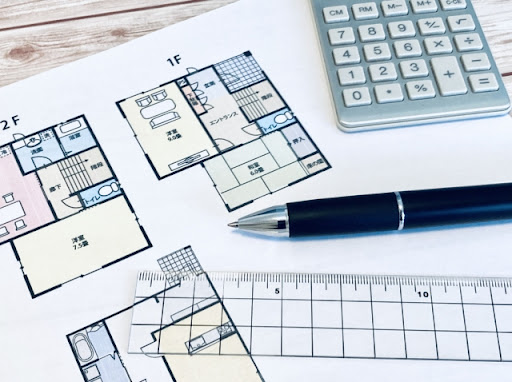 間取り図の上に載った定規とペンと電卓